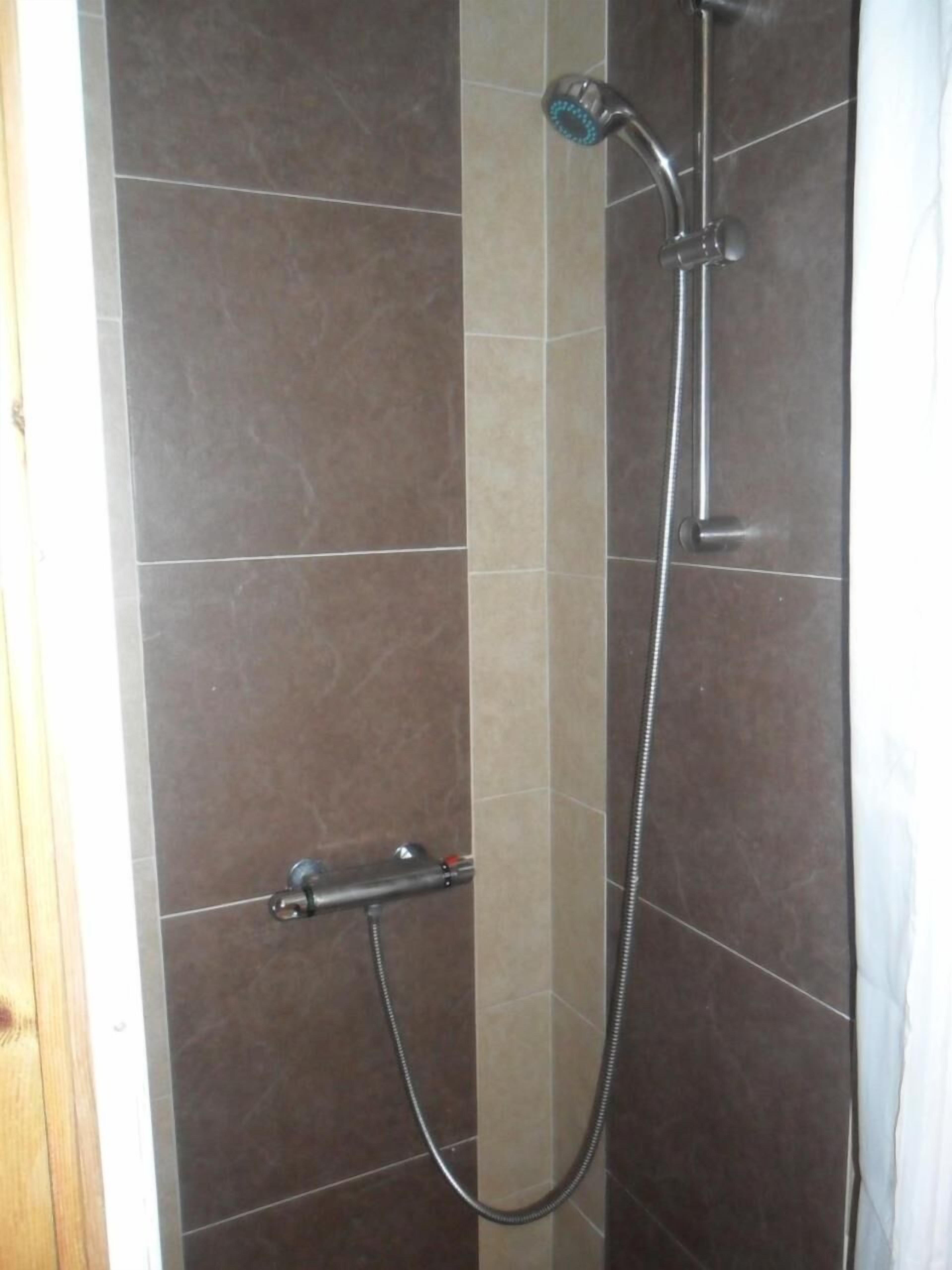 Un espace douche équipé d’un pommeau de douche à main et d’un robinet mural.