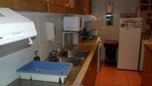 Una cocina con armarios de madera, microondas, fregadero y refrigerador.
