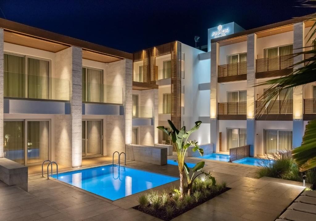Un hotel moderno con zona de piscina, que presenta un diseño contemporáneo con ventanas amplias y un espacio exterior bien iluminado.