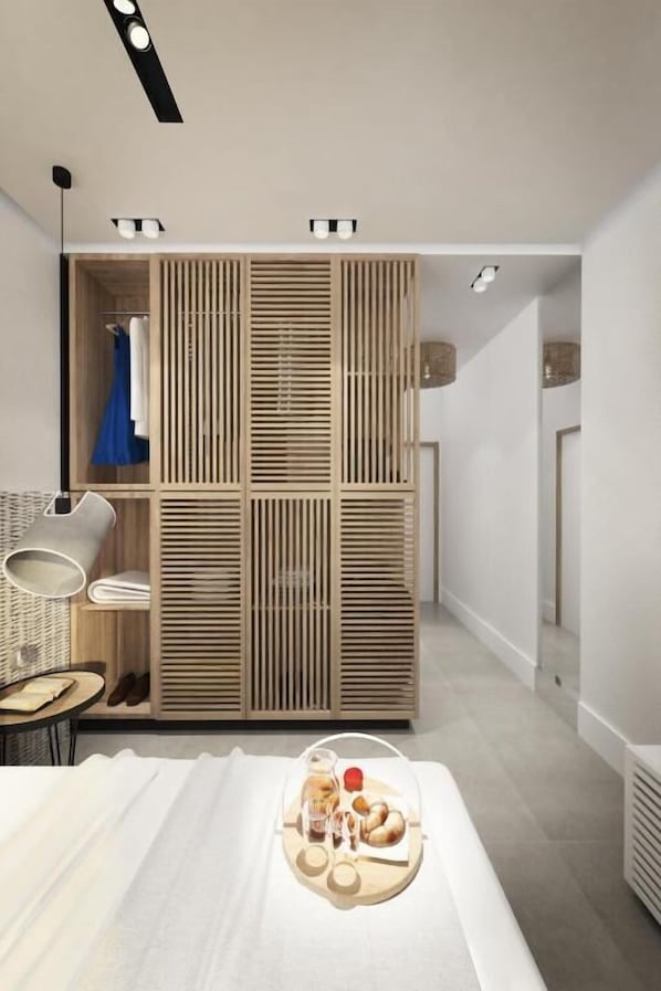 A modern hotel room with a large bed, a wooden wardrobe, a seating area with a chair, and a tray of food. - Enorme Ammos Beach - Adults Only (Hersonissos)
