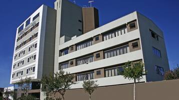 Hotel features a modern facade with a prominent entrance and landscaped outdoor area.