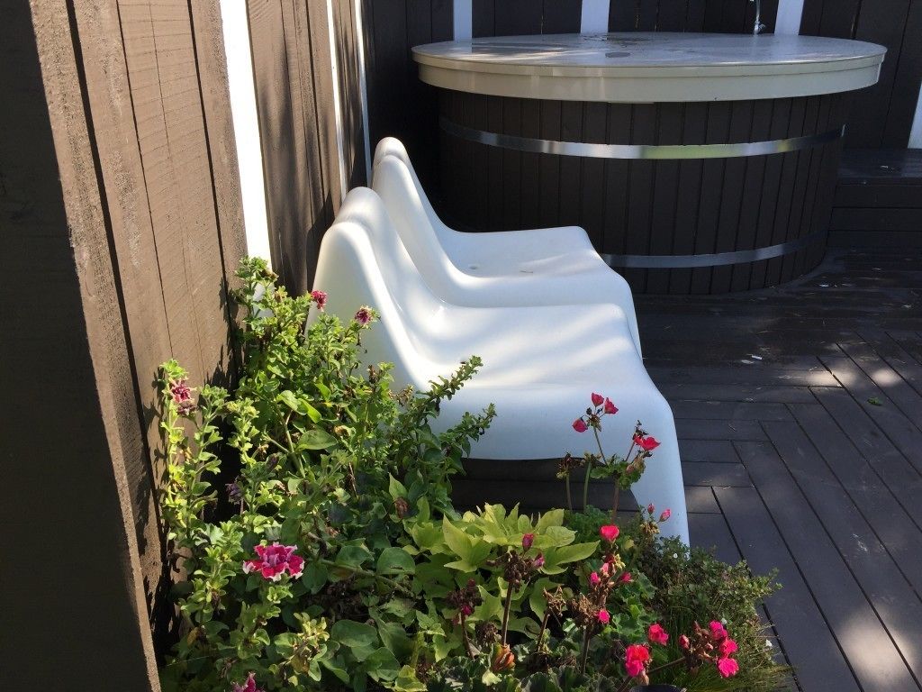 A white plastic chair next to a wooden fence, with a hot tub in the background.