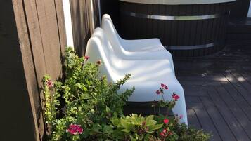 A white plastic chair next to a wooden fence, with a hot tub in the background.