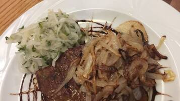 A plate of food with a steak, onions, and a side salad.