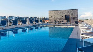 A rooftop pool with lounge chairs and a modern building with a brick facade. - ibis budget Blankenberge (Blankenberge)