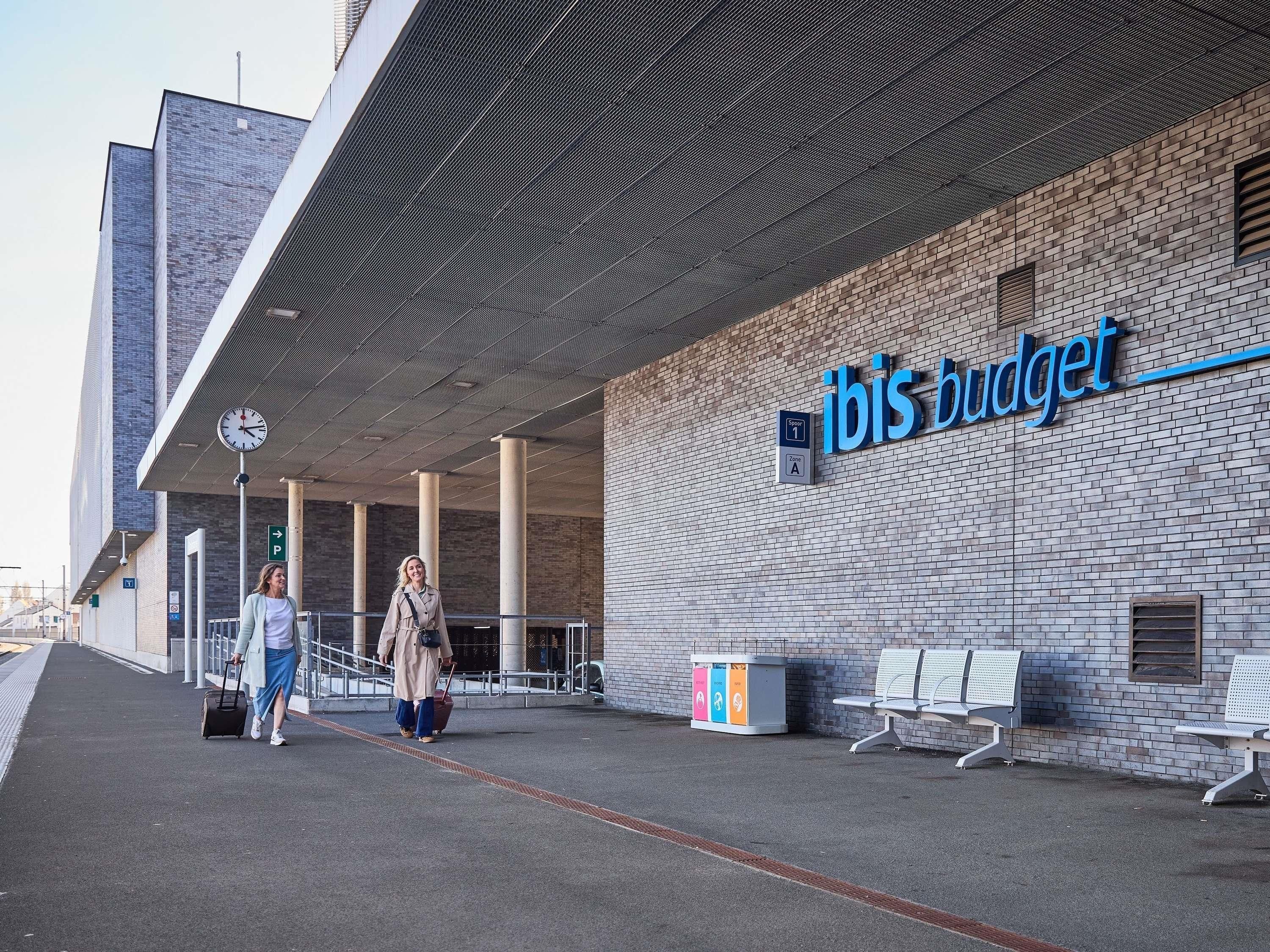 A building with a sign reading 'ibis budget' and a clock above the entrance.