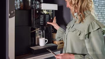 Une personne utilise une machine à café, un récipient étant placé en dessous.
