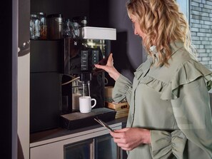 A person operating a coffee machine with a cup placed below it. - ibis budget Blankenberge (Blankenberge)