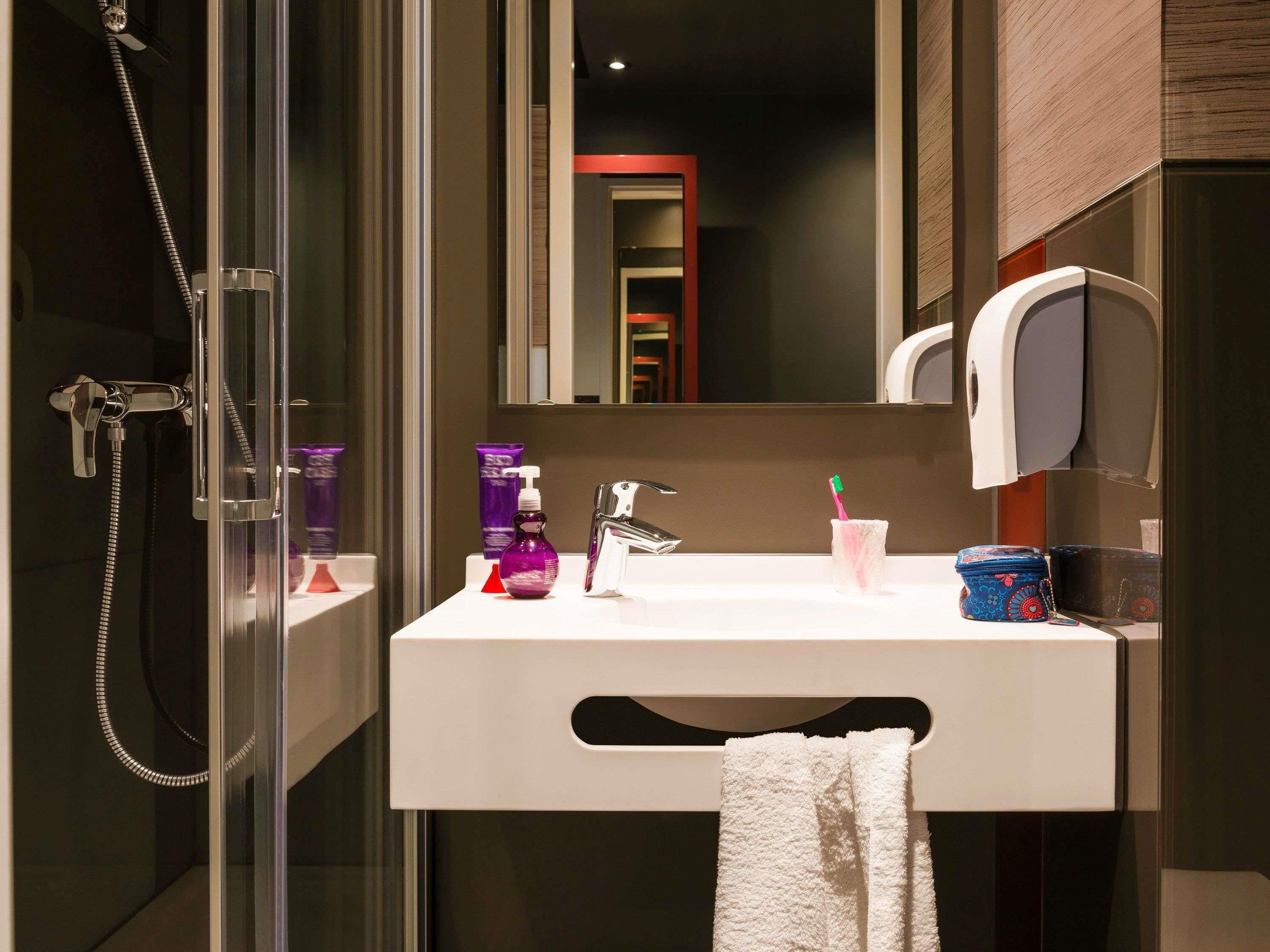 Un baño moderno con cabina de ducha de vidrio, un lavabo blanco y un espejo encima.