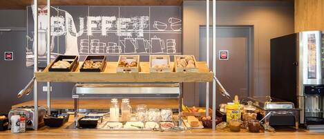 Un comptoir de buffet proposant divers plats, une machine à café et un panneau indiquant « BUFFET ».