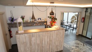 A reception area with a wooden counter, pendant lights, and a small shelf with decorative items. - Hotel L´Escala Centre (L'Escala)