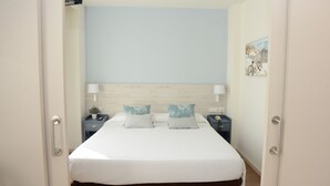 A bedroom with a large bed, two bedside tables, a nightstand, and a wall-mounted lamp. - Hotel L´Escala Centre (L'Escala)