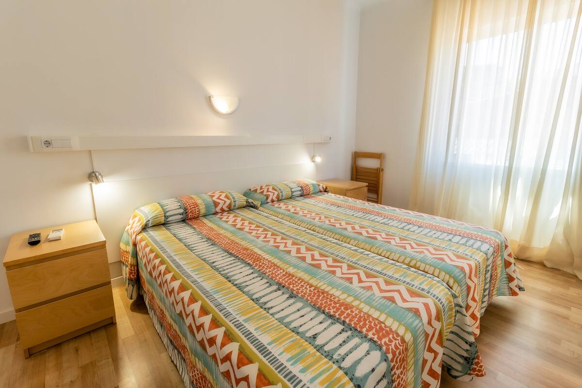 Ein Schlafzimmer mit Bett, Nachttischen und einem Fenster mit Vorhängen.