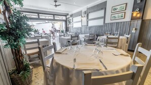 Un restaurant avec des tables rondes recouvertes de nappes blanches, des chaises et des verres à vin.