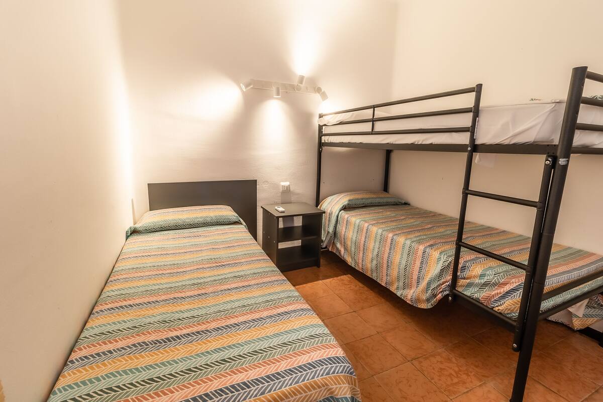 Ein Zimmer mit Etagenbetten, einem Nachttisch und einer Wandleuchte.