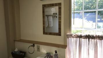 A bathroom with a toilet, sink, and a mirror above the sink.