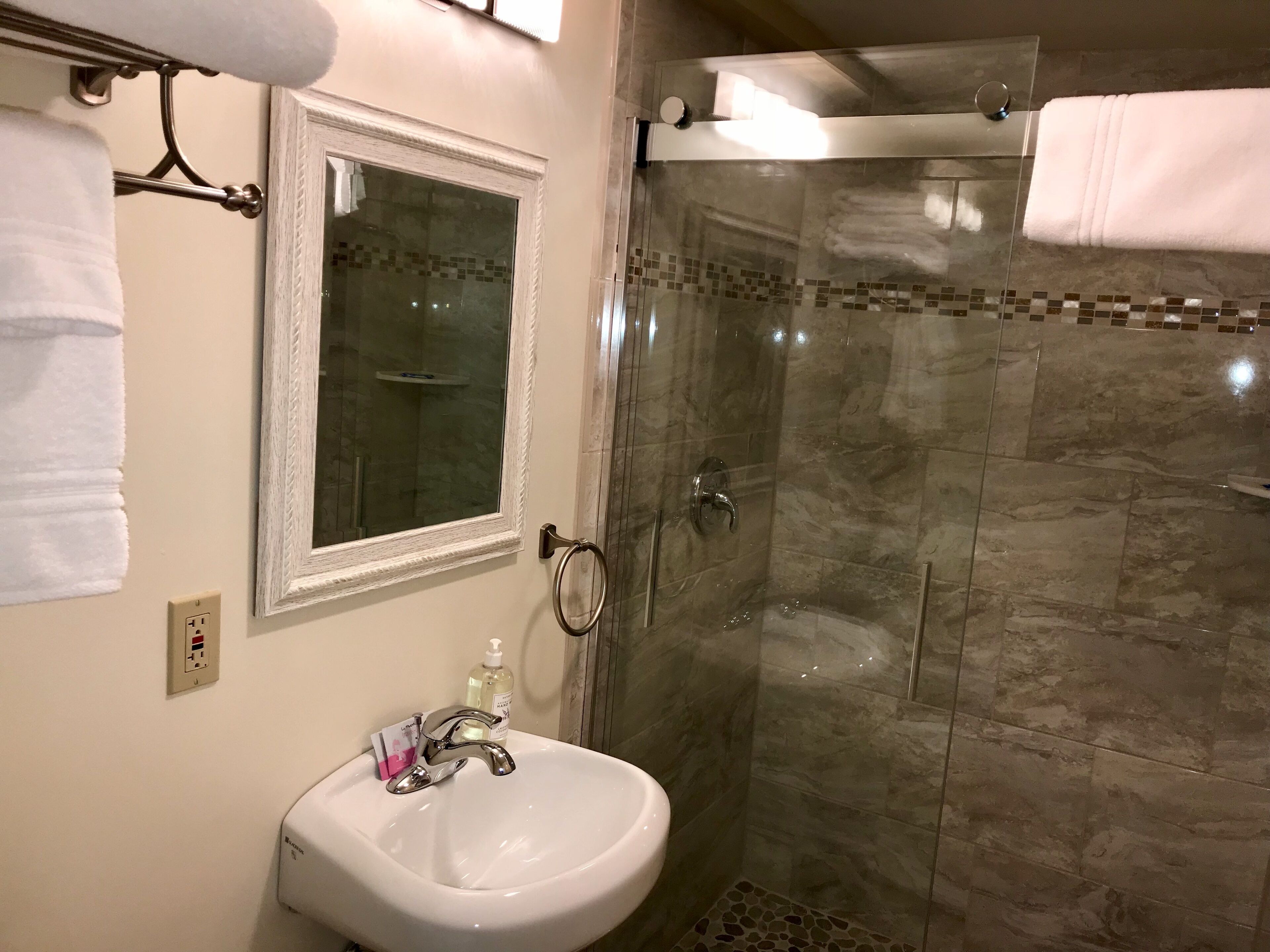 A bathroom with a white sink, a mirror, and a glass-enclosed shower.