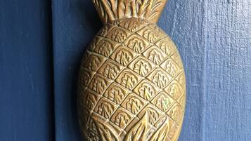 A golden pineapple-shaped door knocker on a blue door.