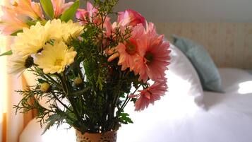 Un ramo de flores en un jarrón decorativo sobre una mesita de noche.