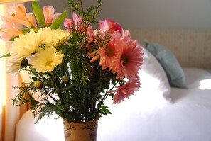 A bouquet of flowers in a decorative vase on a bedside table.