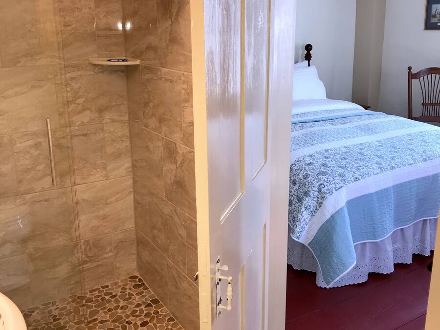 Une salle de bain avec une douche à parois de verre, un lavabo blanc et un sol carrelé.