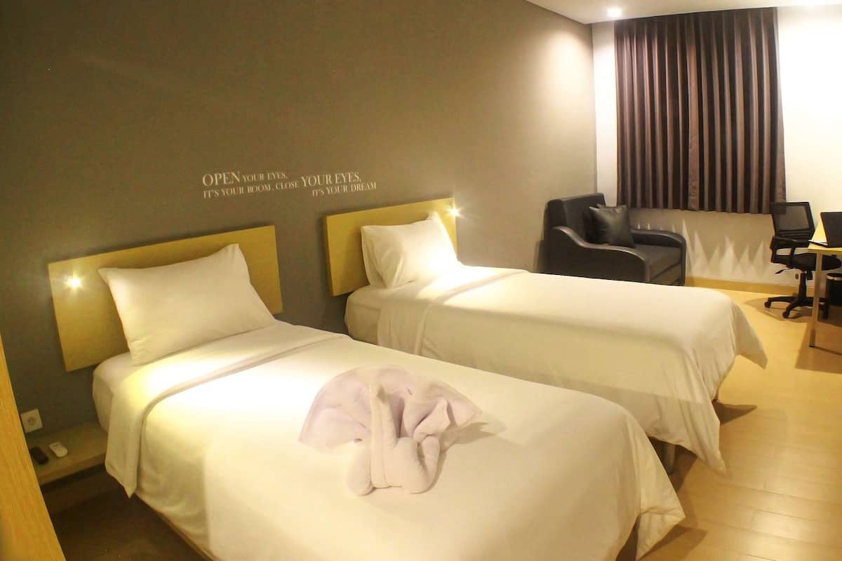 A hotel room with two beds, a desk, and a chair.