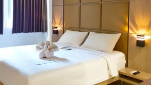 A neatly made bed with white linens, a towel, and a remote control on a bedside table. - Kyriad Hotel Fatmawati - Jakarta (Jakarta)