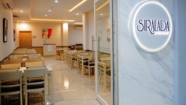 A modern restaurant interior with a marble wall and a neon sign reading "SIRALADA restaurant". - Kyriad Hotel Fatmawati - Jakarta (Jakarta)