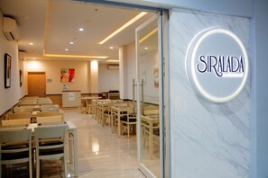 A modern restaurant interior with a marble wall and a neon sign reading "SIRALADA restaurant". - Kyriad Hotel Fatmawati - Jakarta (Jakarta)