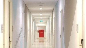 A long, well-lit hallway with doors on both sides, leading to a red exit sign at the end. - Kyriad Hotel Fatmawati - Jakarta (Jakarta)