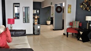 A living room with a sofa, two red chairs, a coffee table, a lamp, and a potted plant.