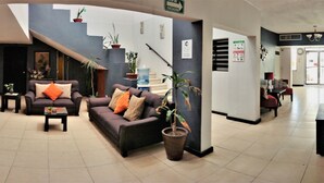 A spacious lobby with a reception desk, seating area, and potted plants.