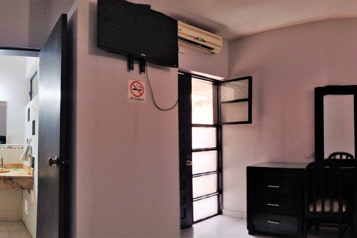 A bedroom with a bed, a dresser, a mirror, and a door leading to a bathroom.