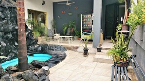 A pool area with a stone wall, a small pool, and a seating area with chairs and a table.