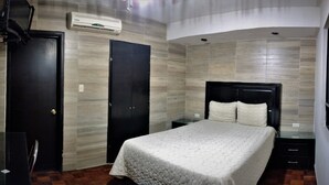 A bedroom with a bed, a wardrobe, and an air conditioning unit.