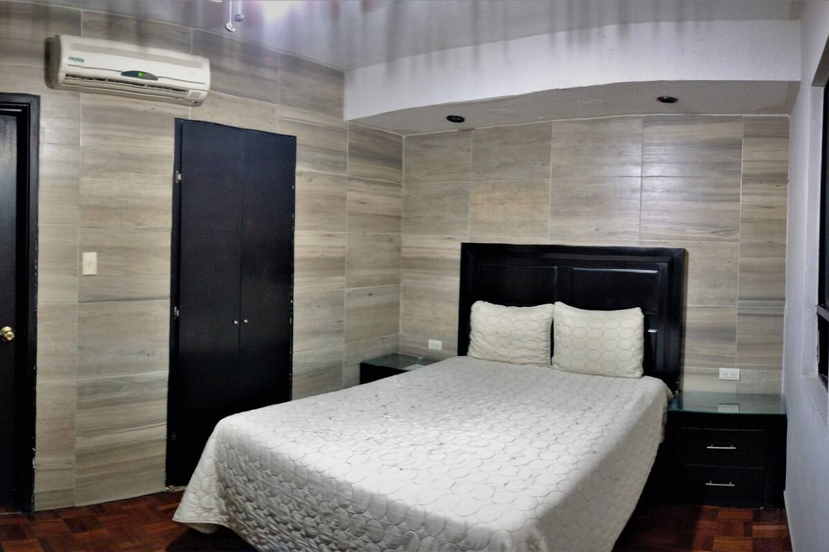 A bedroom with a bed, a wardrobe, and an air conditioning unit.