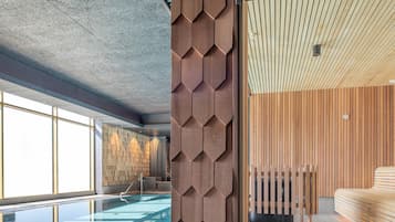 A modern hotel interior with a swimming pool, wooden panel walls, and a ceiling with a geometric pattern.