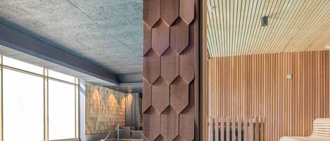 A modern hotel interior with a swimming pool, wooden panel walls, and a ceiling with a geometric pattern.