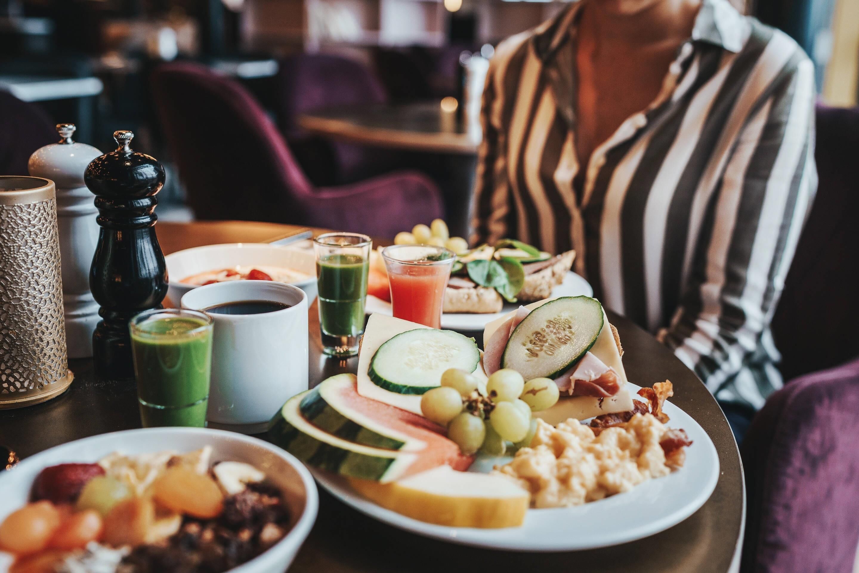 Una mesa de comedor con alimentos para el desayuno, incluyendo frutas, queso y bebidas.