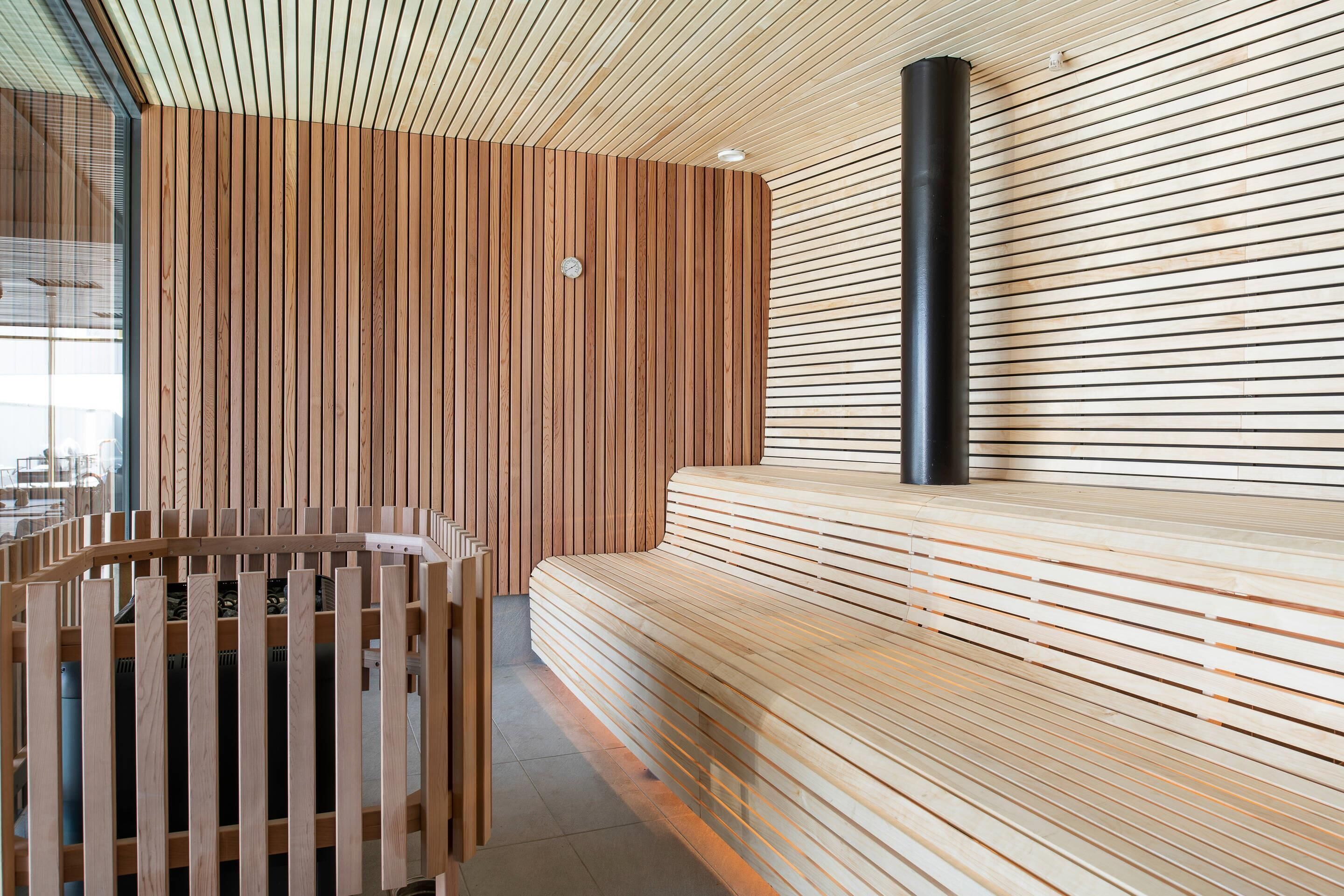 A modern interior with a wooden slatted wall, a bench, and a cylindrical black object.