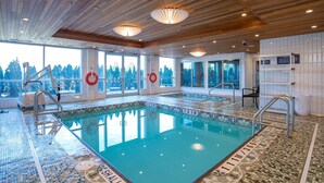 Una piscina interior con techo de madera, ventanas amplias y boyas salvavidas.
