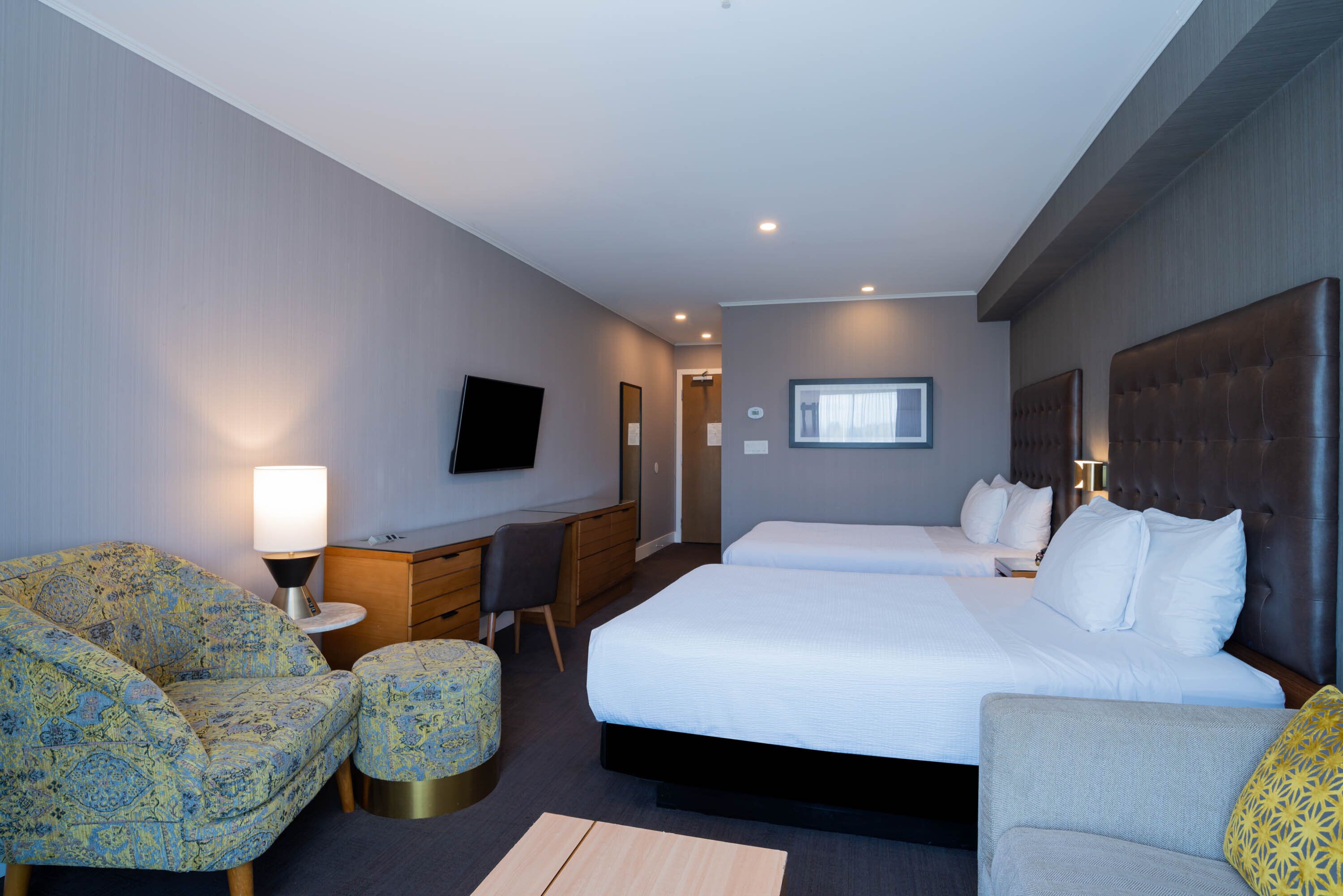 A hotel room with a large bed, two bedside tables, a desk, a chair, and a TV.