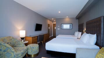 A hotel room with a large bed, two bedside tables, a desk, a chair, and a TV.