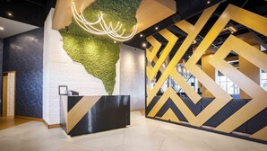 Una moderna zona de recepción con una pared verde, un mostrador negro y paredes con patrones geométricos.