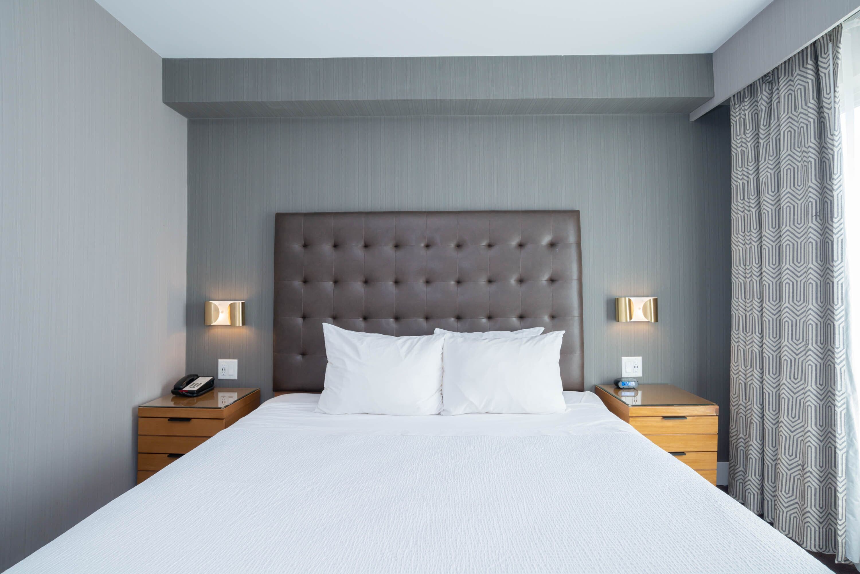 Une chambre d’hôtel avec un grand lit, deux tables de chevet et une tête de lit.