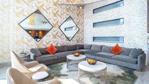 Una sala moderna con un sofá modular, mesas redondas de centro y un papel tapiz estampado.