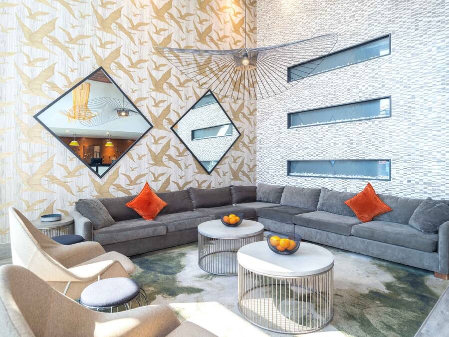 Una sala moderna con un sofá modular, mesas redondas de centro y un papel tapiz estampado.