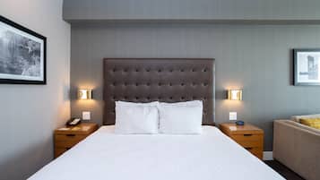 A neatly made bed with white linens, two bedside tables with lamps, and framed pictures on the walls.