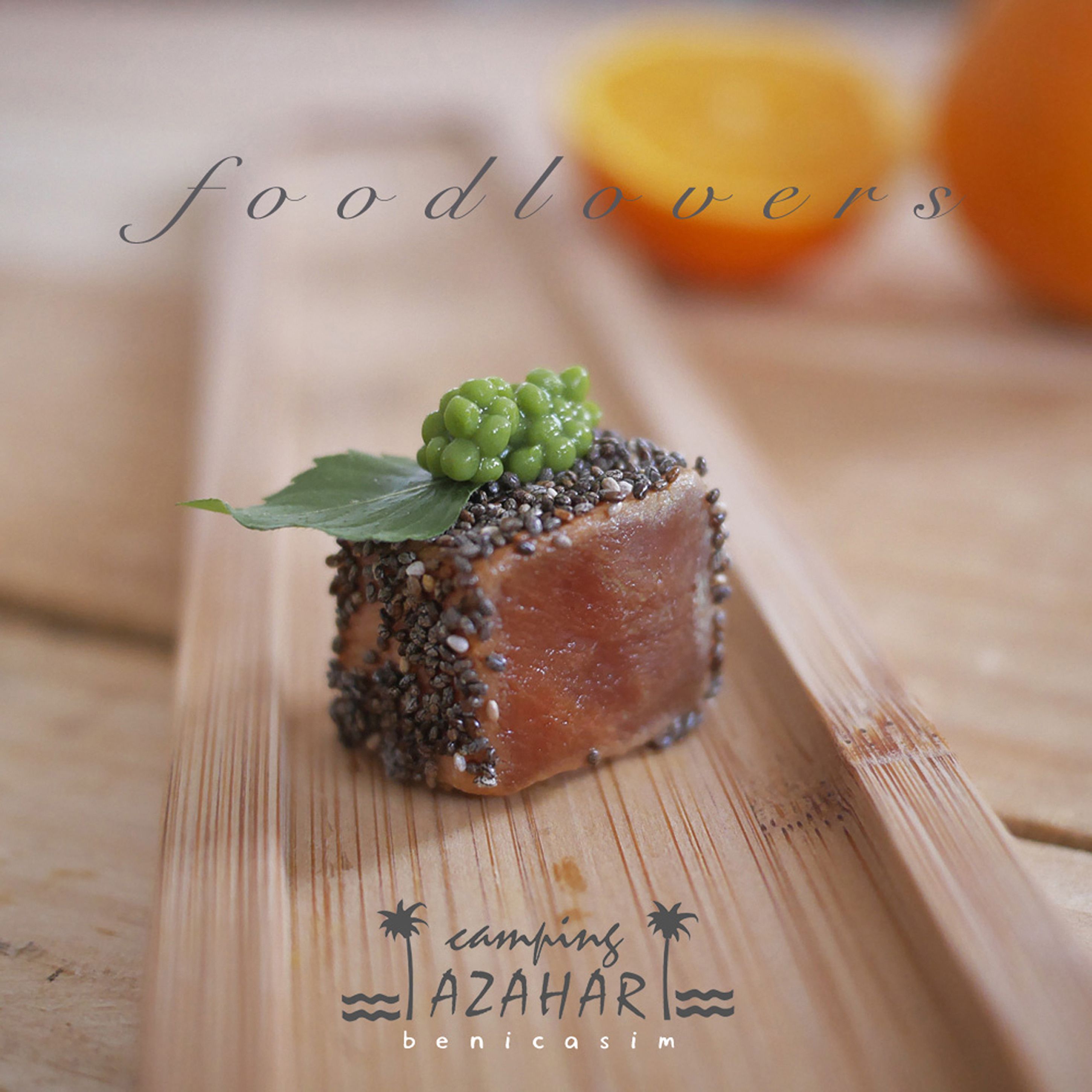 Un alimento sobre una tabla de madera con el texto 'foodlovers' y 'camping AZAHAR benicassim'.