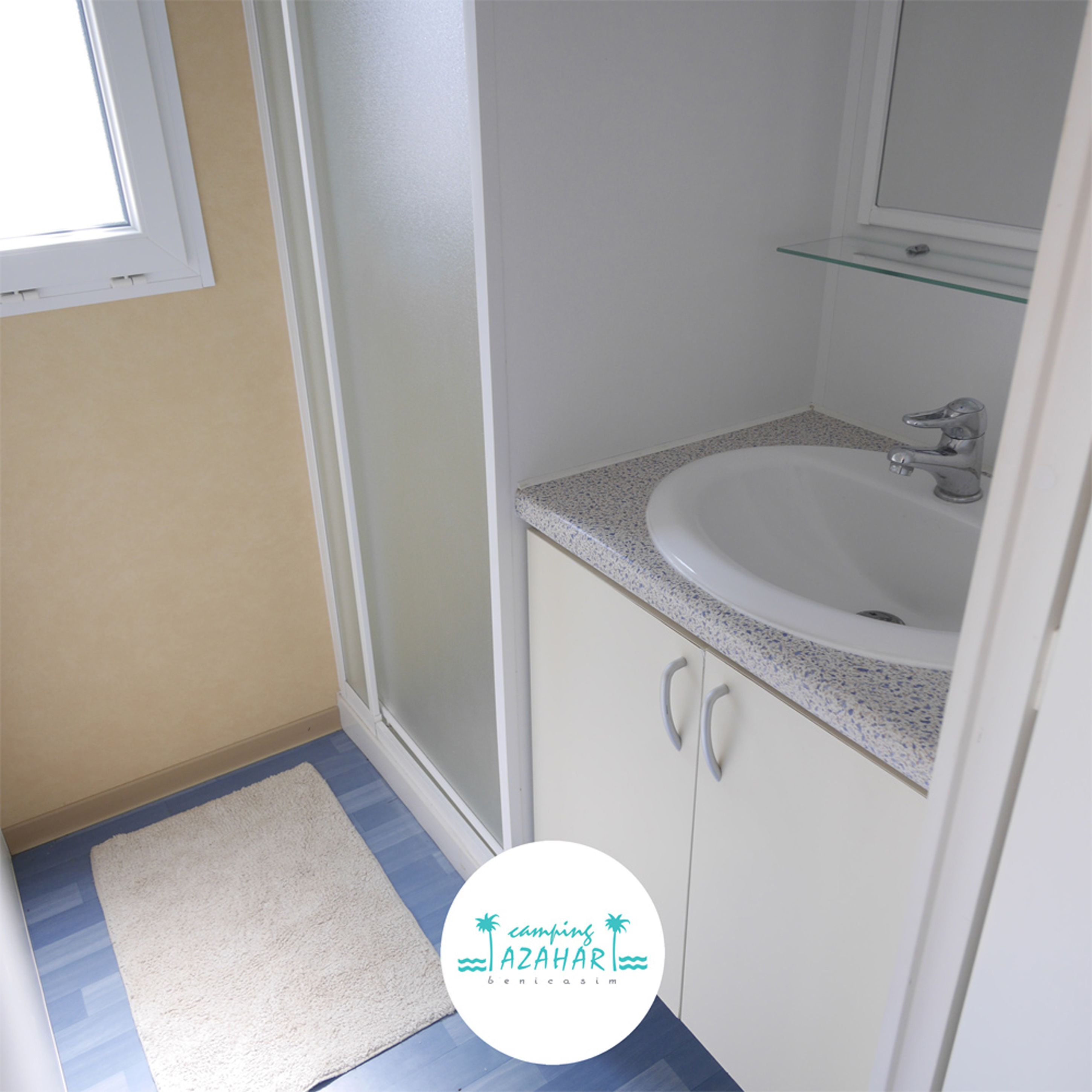 A bathroom with a white sink, a glass shelf above it, and a white door.